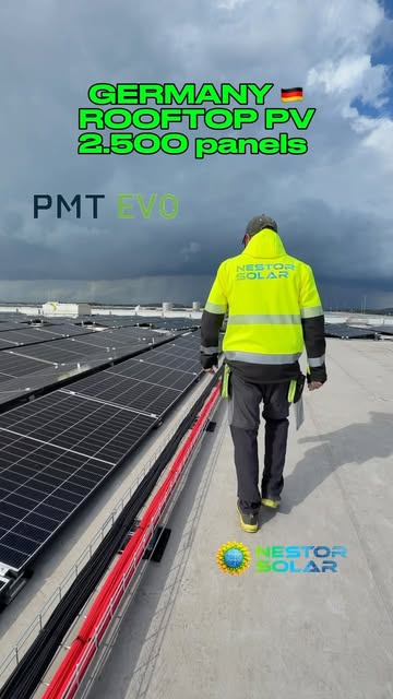 Installer inspecting rows of rooftop solar panels in Germany
